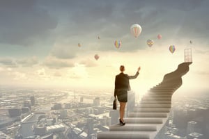 Businesswoman walking up staircase to door in sky