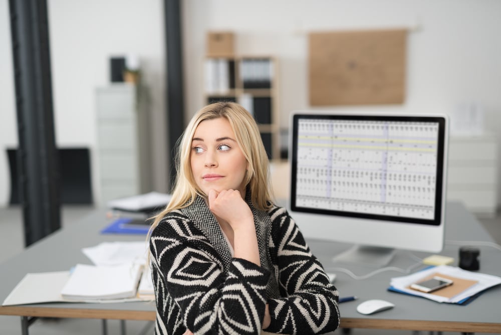 Young woman sitting in the office daydreaming turning in her chair to stare pensively off to the side with a serious expression and her chin resting on her hand Young woman sitting in the office daydreaming turning in her chair to stare pensively off to the side with a serious expression and her chin resting on her hand